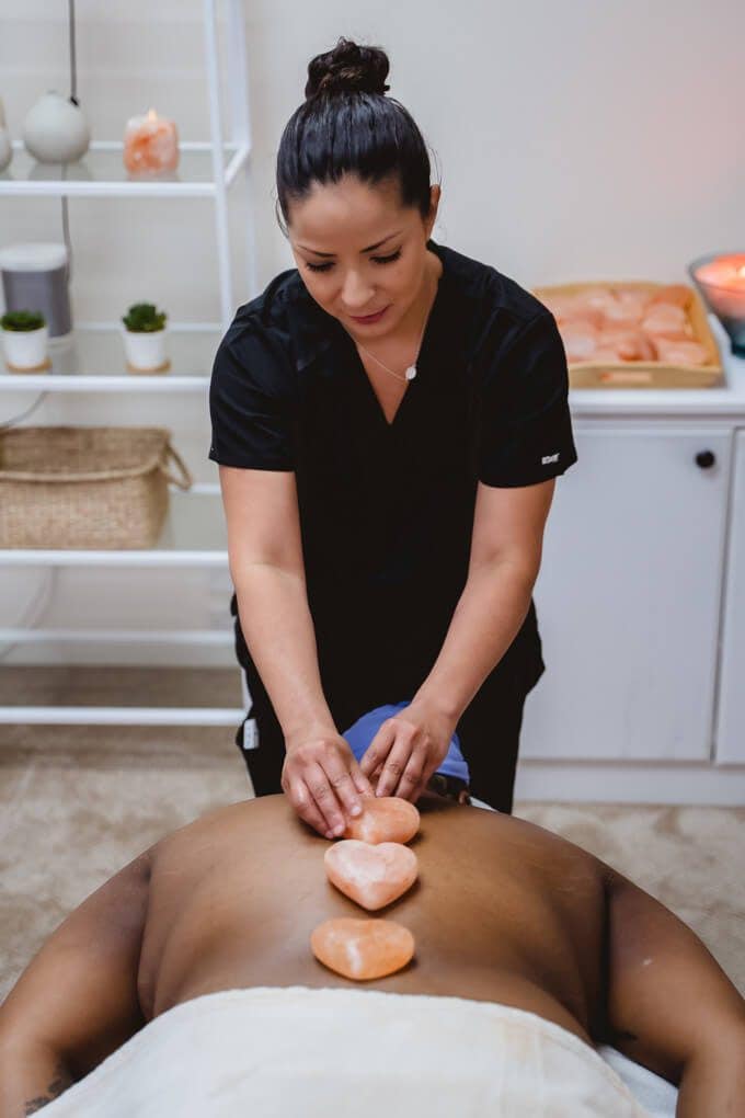 A therapist performing a hot stone massage on a client