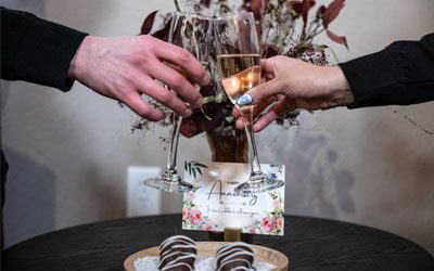 Maria-Spa1 Two people clink champagne flutes over a small table
