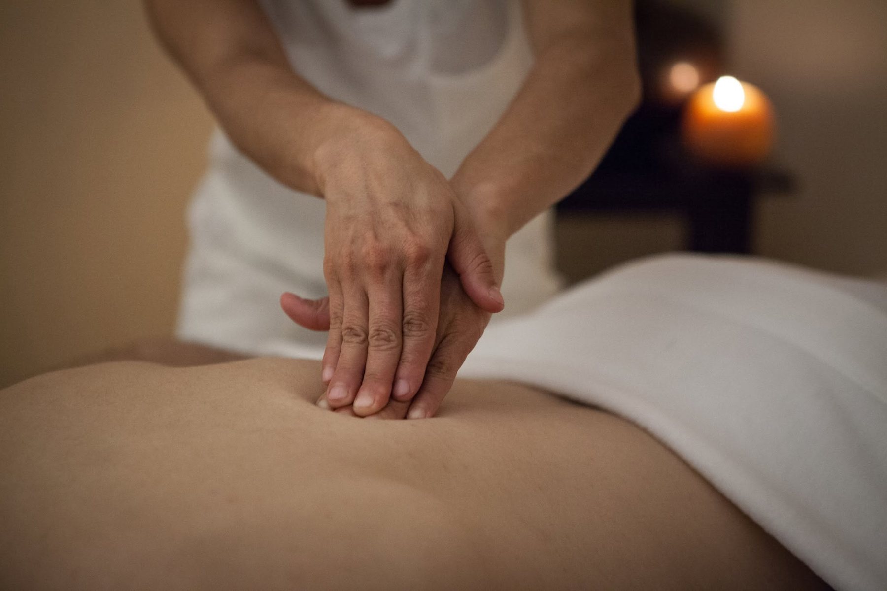A therapist performing a massage by candlelight at Zen'd Out