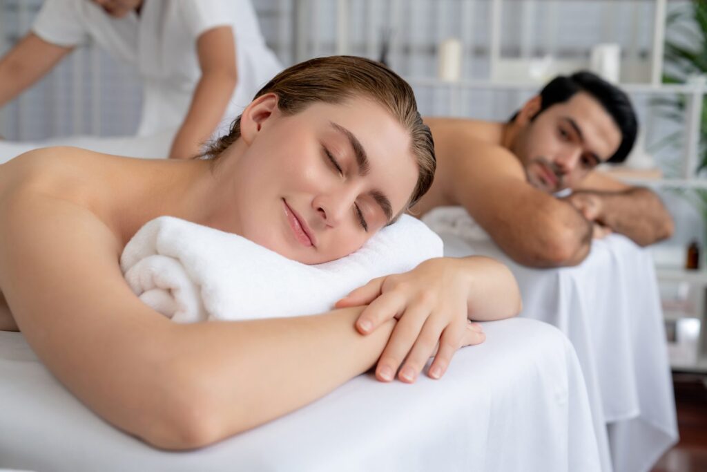 Woman resting her head on a towel with eyes closed next to her partner during a couples massage