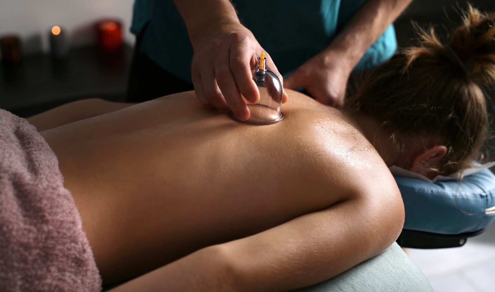 Therapist gliding a cup along a guest's back during dynamic cupping