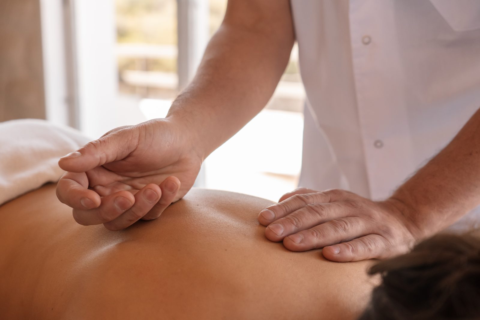 Massage therapist's hands working on a guest's back