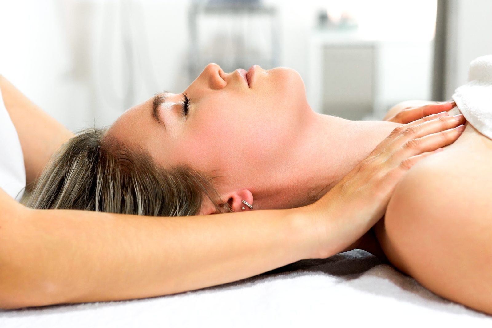 Woman with eyes closed receiving a gentle neck and shoulder massage