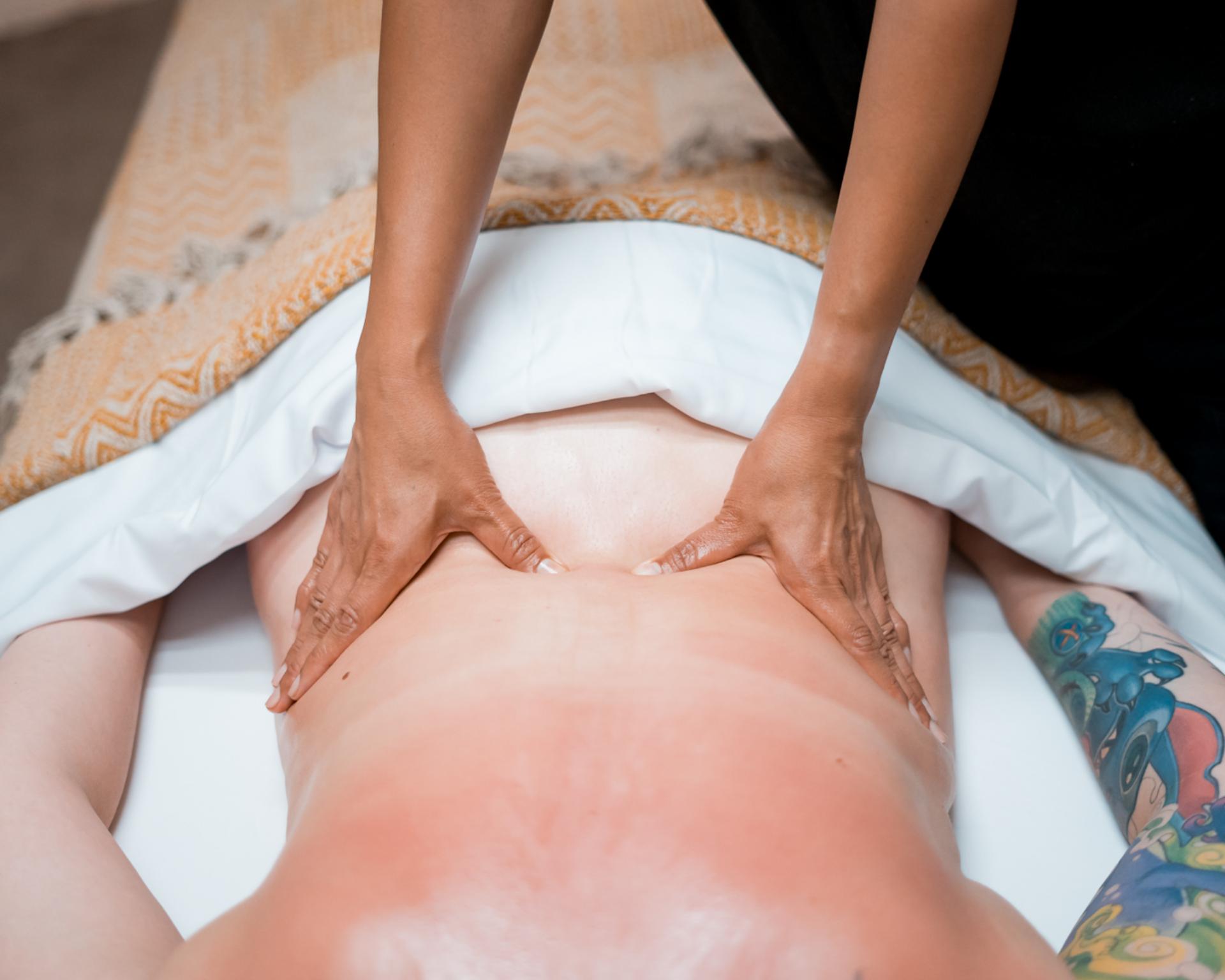 Deep tissue back massage on the lower back for a guest at Zen'd Out Massage Spa in Englewood, CO