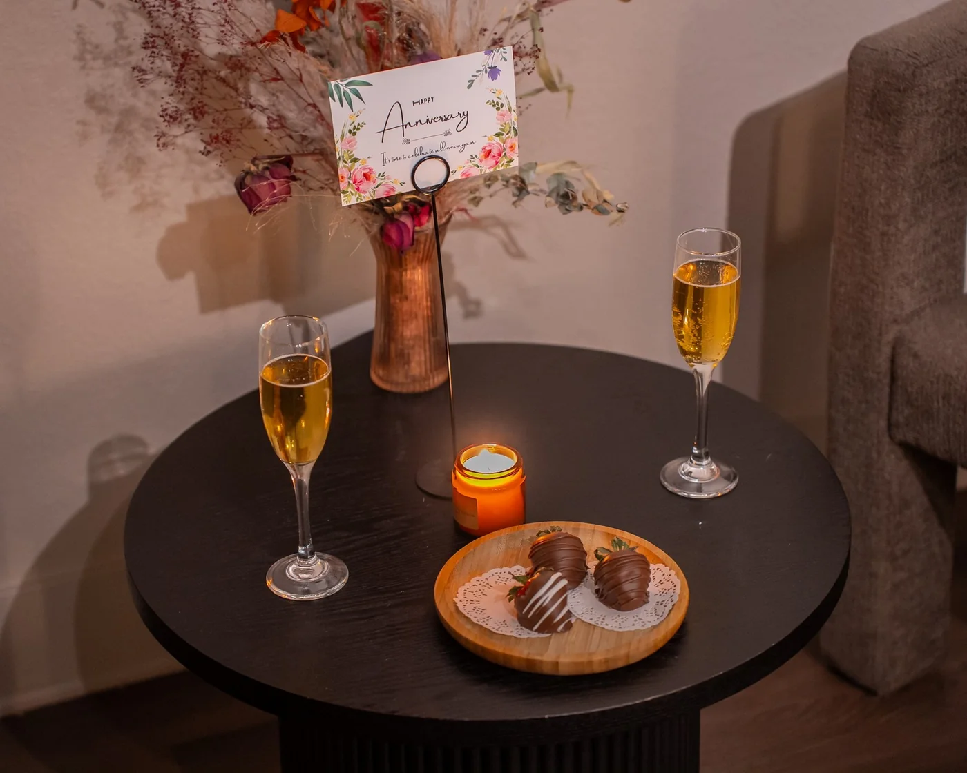 Day Spa at Zend Out Massage Spa Denver 31 Anniversary card, chocolate-covered strawberries, celebration beverages and candle on side table.